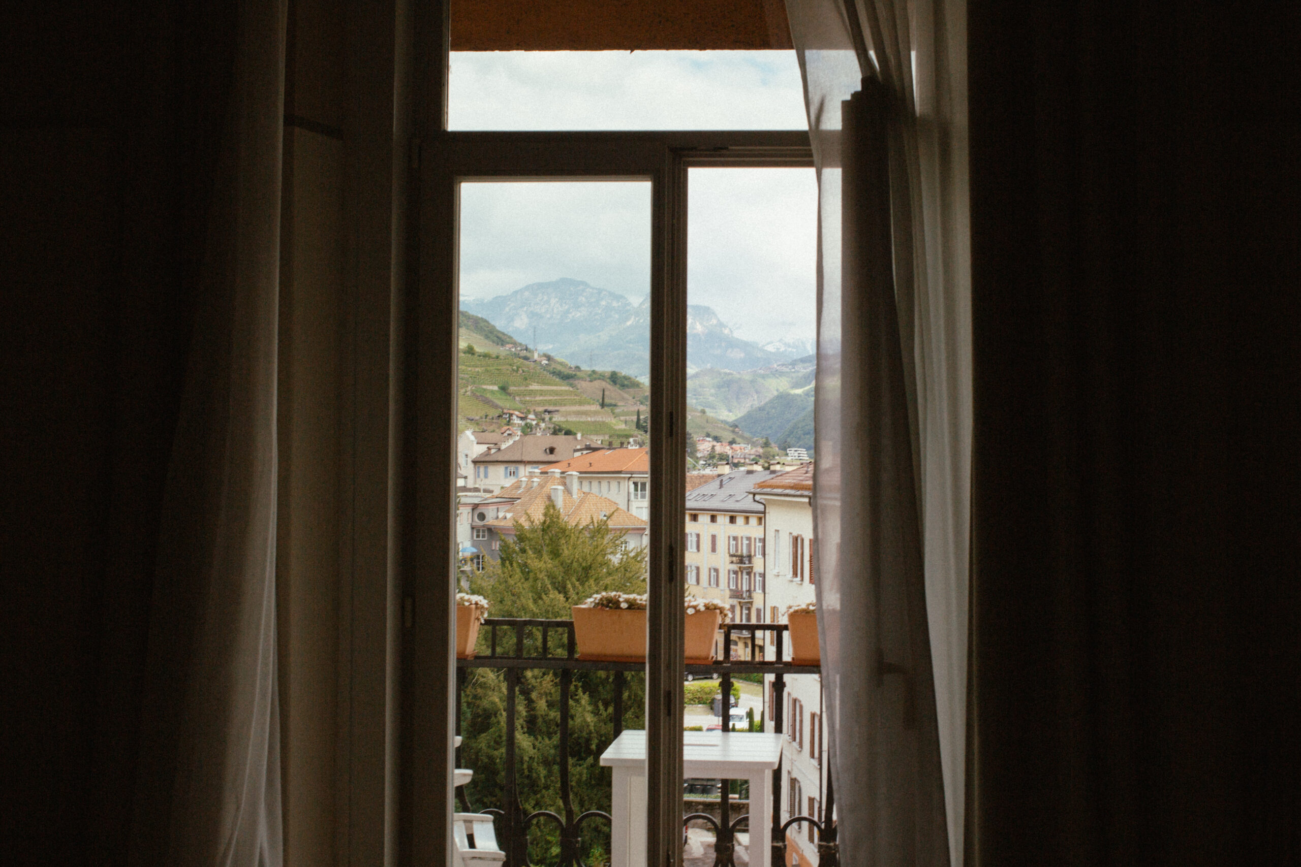 view of a balcony and the town below from inside of a room with curtains on the side