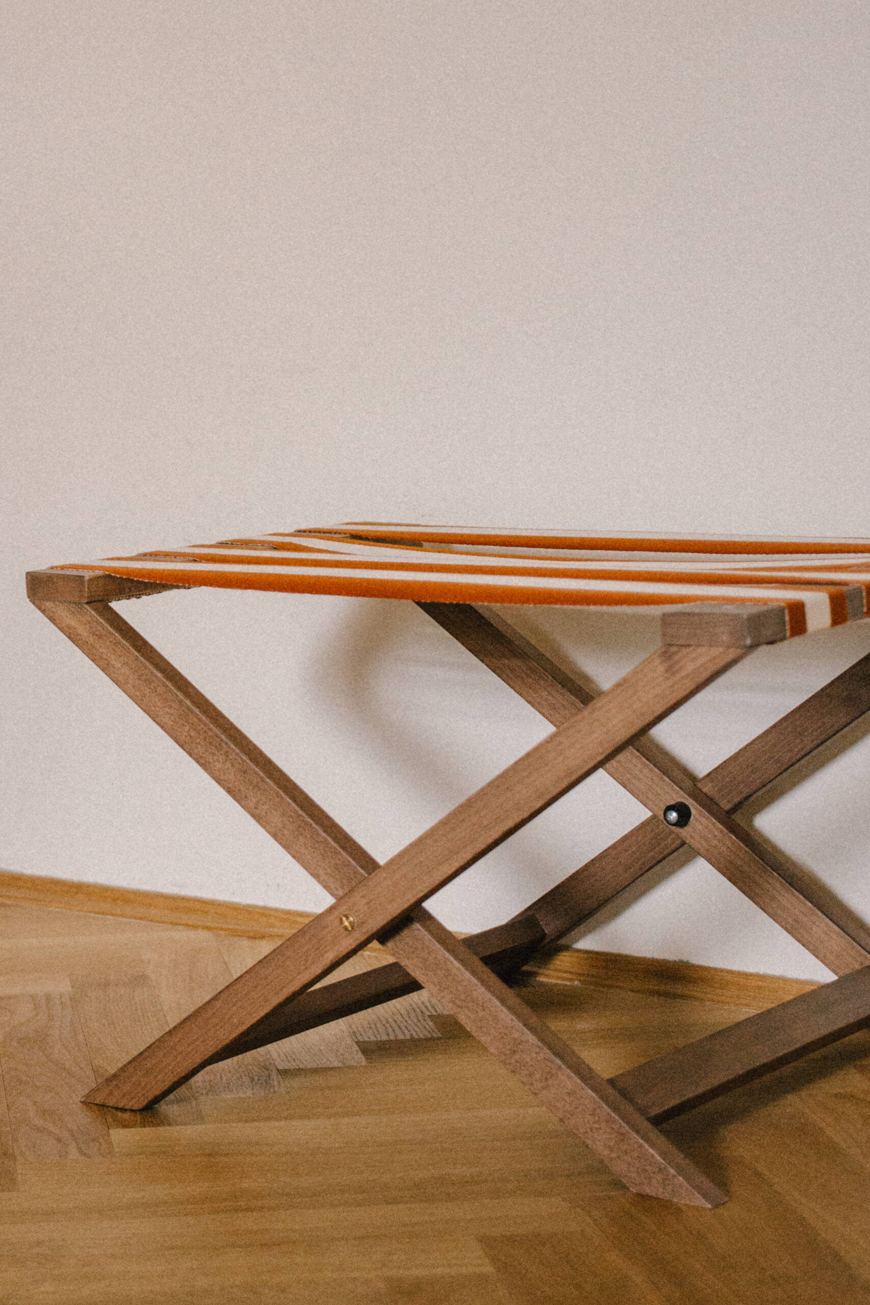 striped wooden luggage holder in a hotel room